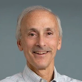 middle-aged man with gray moustache and hair smiles into camera