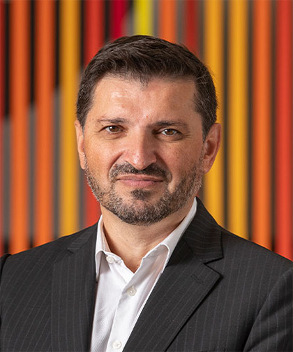 middle aged man with dark hair and beard looks into camera