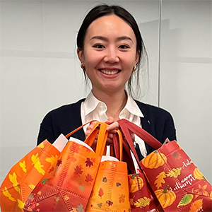 Young woman in black sweater holds many brightly colored bags filled with gifts