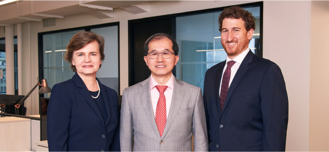 Bluestar partners Trzcinska, Zhang, and Eskow in business attire, standing in office